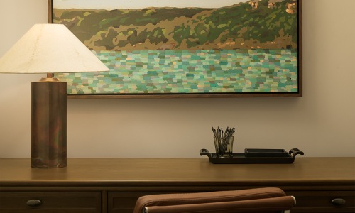 a desk with a lamp and wall art